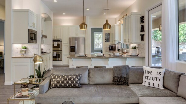 A modern living room with a grey sectional sofa, a glass coffee table, and decorative vases. - Walk to Coachella! 7BR~Sleeps 14~Pool~Game Room! (Indio)