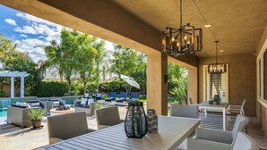 An outdoor patio with a pool, lounge chairs, and a dining area. - Walk to Coachella! 7BR~Sleeps 14~Pool~Game Room! (Indio)