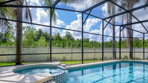 Una piscina con idromassaggio, circondata da una recinzione metallica e palme.