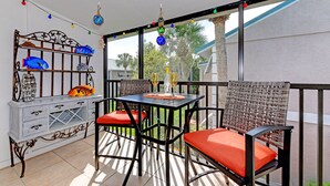 A balcony with a table and chairs, decorated with string lights and a fish-themed shelf. - Siesta Key Beach IDEAL LOCATION BEACH, VILLAGE, HEATED POOL (Siesta Key)