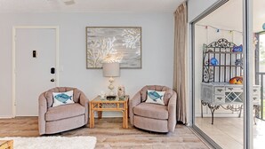 A cozy living room with two armchairs, a side table, and a large window with a view of a balcony. - Siesta Key Beach IDEAL LOCATION BEACH, VILLAGE, HEATED POOL (Siesta Key)