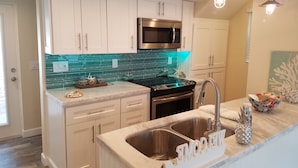 A modern kitchen with white cabinets, a stainless steel sink, and a black stove.