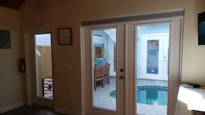 A hallway with a door leading to a pool area, a fire extinguisher, and a framed picture on the wall.