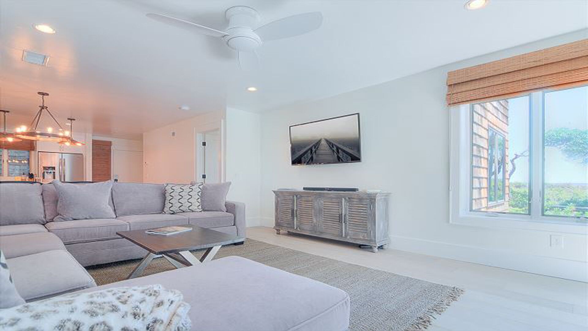 A modern living room with a sofa, coffee table, and a television on a cabinet.