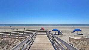 A wooden boardwalk leading to a beach with blue umbrellas and a clear blue sky. - Spectacular 1 Bedroom, Oceanfront Villa! BRAND NEW RENOVATION!! (Kiawah Island)