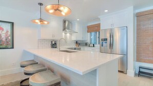 A modern kitchen with a large island, stainless steel appliances, and pendant lighting. - Spectacular 1 Bedroom, Oceanfront Villa! BRAND NEW RENOVATION!! (Kiawah Island)