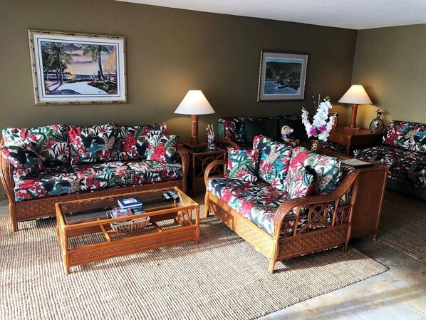 A living room with two sofas, a coffee table, and two lamps. There are framed pictures on the wall. - Kona Alii 306 Oceanfront Corner Condo, Amazing View in the Heart of Kona (Kailua-Kona)