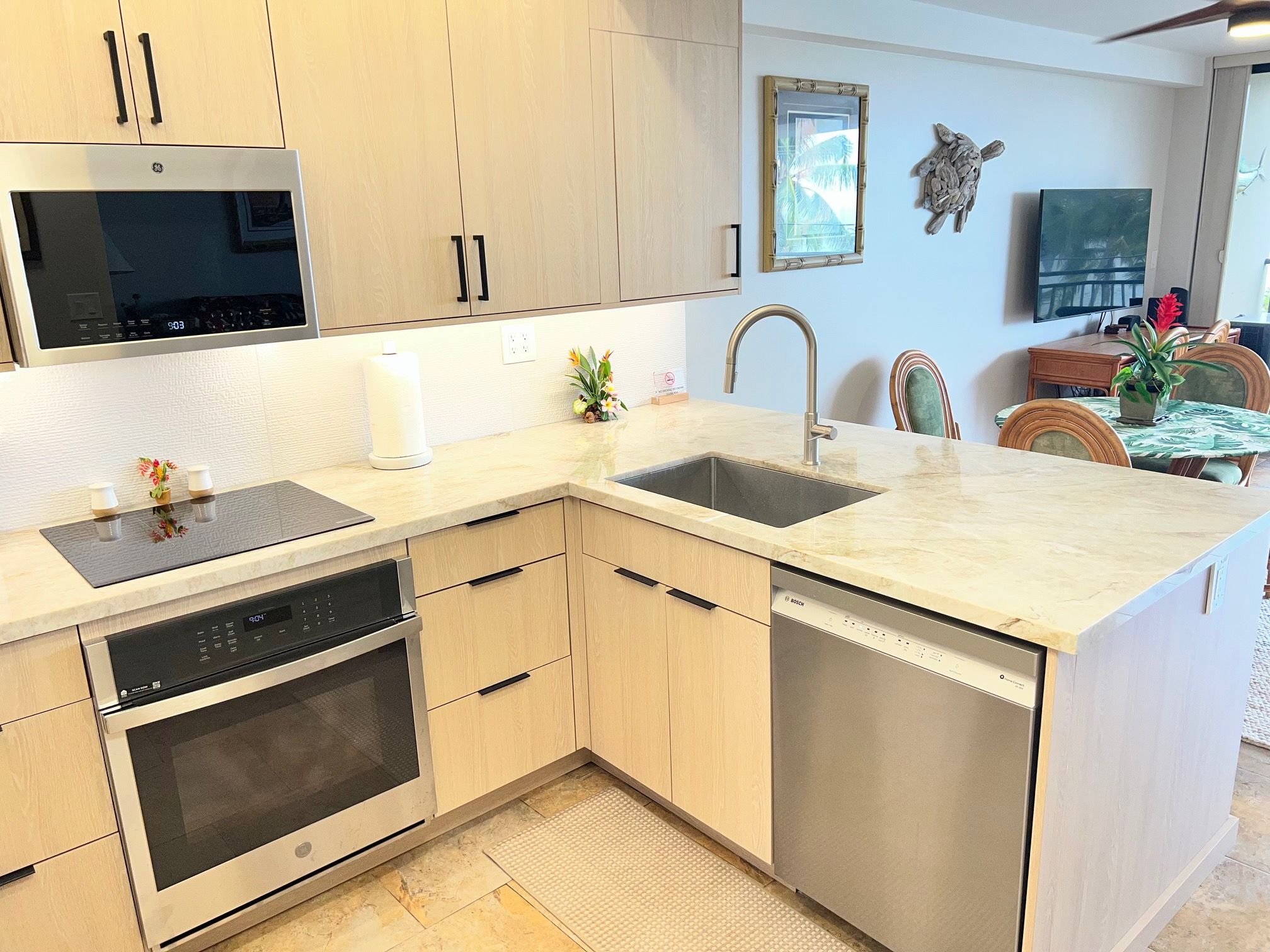 Una cocina moderna con electrodomésticos integrados, una isla grande con pileta y una zona de comedor con mesa y sillas.