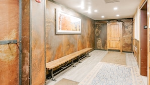 Un pasillo con un banco de madera, un cuadro enmarcado en la pared y una puerta de madera.