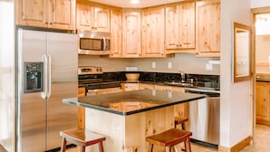 Una cocina con armarios de madera, electrodomésticos de acero inoxidable y una isla central con taburetes.