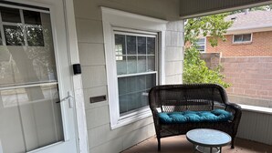 Une véranda avec une chaise en osier et une petite table.
