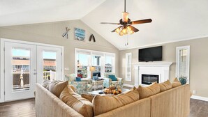 A living room with a sectional sofa, a fireplace, and a television. - Canal House 2 short blocks to the beach with beach access! (Ocean Isle)
