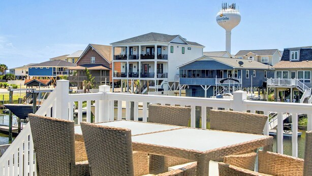 A waterfront property with a white fence, wicker furniture, and a water tower. - Canal House 2 short blocks to the beach with beach access! (Ocean Isle)
