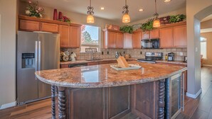 A modern kitchen with granite countertops, stainless steel appliances, and wooden cabinetry.