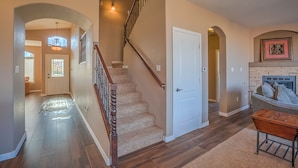 A spacious living area with a wooden staircase, a fireplace, and a cozy seating area.