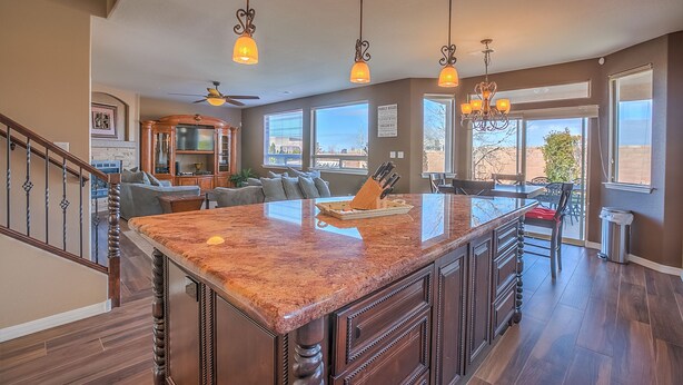 A spacious kitchen with a large island, pendant lighting, and a view to the outside.