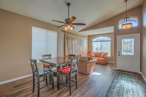 A dining area with a wooden table and chairs, a ceiling fan, and a patterned rug.