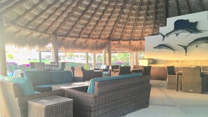 Un espace extérieur aménagé, abrité et doté de mobilier en osier et d’un toit de chaume.
