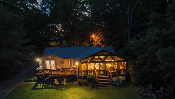 Een chalet met een veranda, buitenmeubels en een zwembad.
