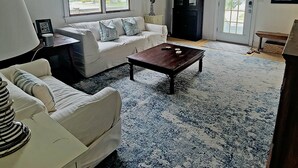 A living room with a white sofa, a coffee table, and a patterned rug. - July 4-11 & Jul 11-18 last-minute availability! (Rehoboth Beach)
