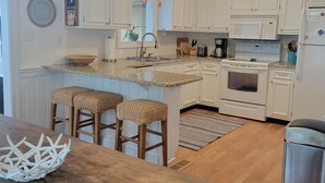 A modern kitchen with white cabinets, a granite countertop, a built-in oven, and a stainless steel refrigerator. - July 4-11 & Jul 11-18 last-minute availability! (Rehoboth Beach)