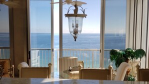 A room with a view of the ocean, a hanging lamp, and a potted plant.