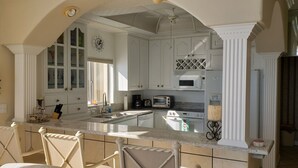 A kitchen with white cabinetry, a central island, a microwave, a toaster, and a clock on the wall.