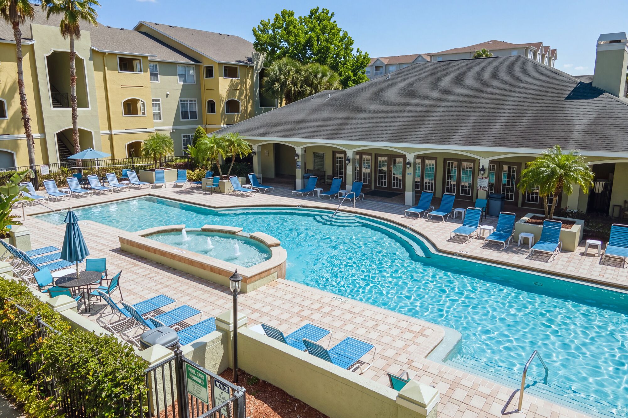 Une piscine dotée de chaises longues et d’un jacuzzi, le tout entouré d’un bâtiment comportant de nombreux balcons.