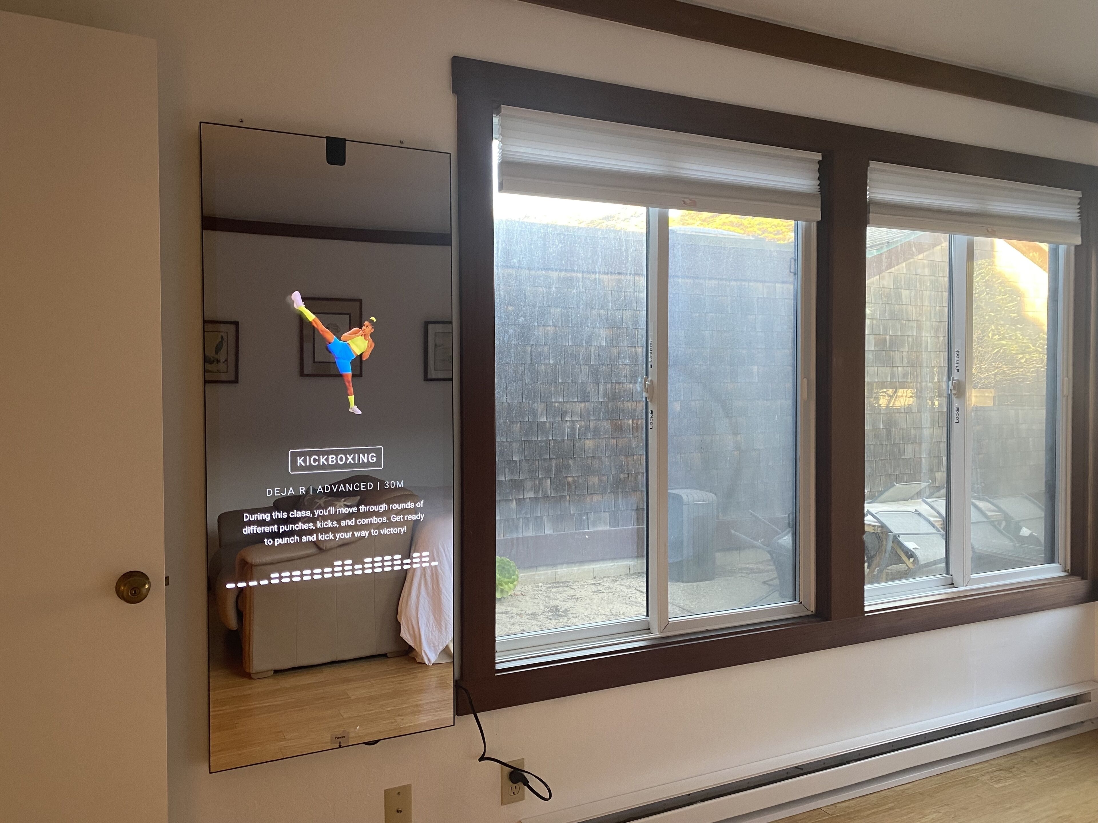 Ein Zimmer mit großem Fenster, einem Wandspiegel und einer Tür.