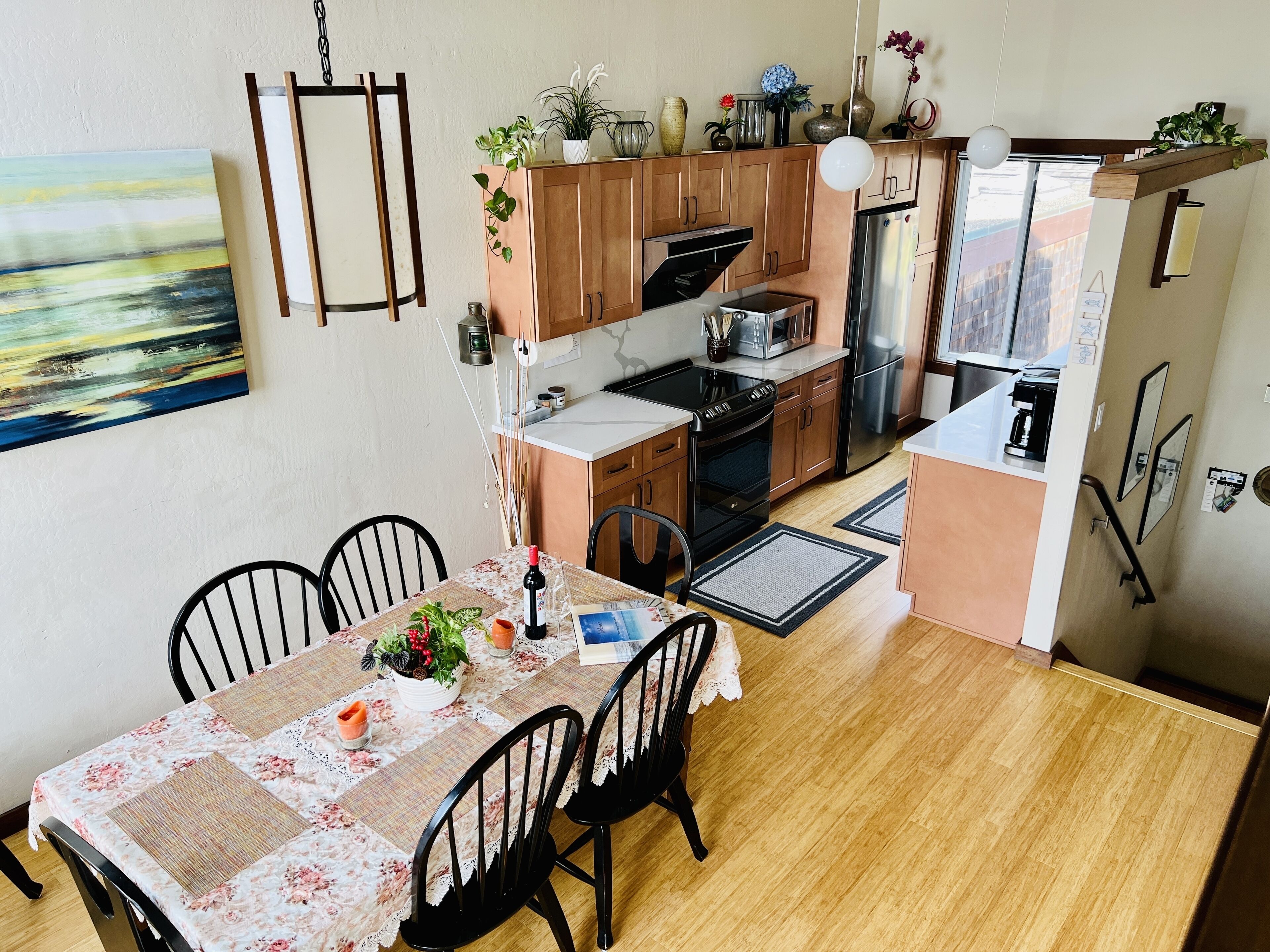 A compact kitchen with wooden cabinets, a microwave, oven, and a refrigerator. There is a dining table with chairs and a floral tablecloth.