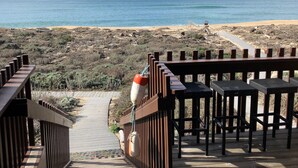 Una terraza de madera que da a una playa con vistas al océano.