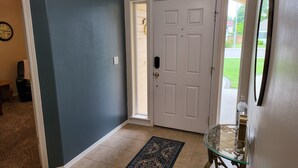 A hallway with a white door, a glass table, and a patterned rug. - Tri-Cities Home Away From Home (Richland)