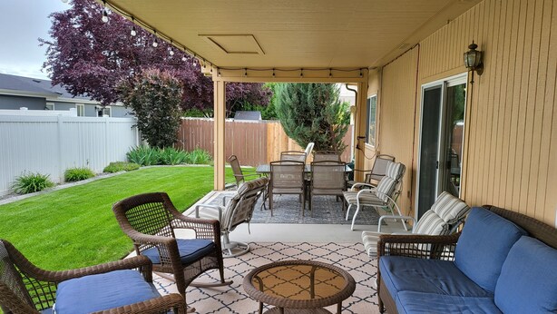 A covered patio area with outdoor furniture, including wicker chairs and a sofa, and a table. - Tri-Cities Home Away From Home (Richland)