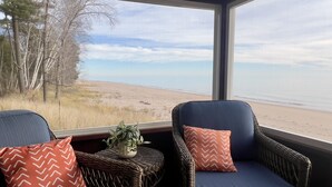 A room with two wicker chairs facing a large window overlooking a beach. - Private Beach, Outdoor Dining, Firepit (Oostburg)