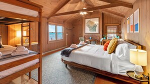 A cozy wooden cabin bedroom with bunk beds, a large bed, a desk, and a view of the sea. - Private Beach, Outdoor Dining, Firepit (Oostburg)