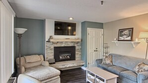 A living room with a fireplace, a sofa, a chair, a coffee table, and a lamp.