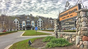 A large, multi-story building with a prominent entrance and a stone sign indicating 'Mountain Grand Lodge and Spa'.