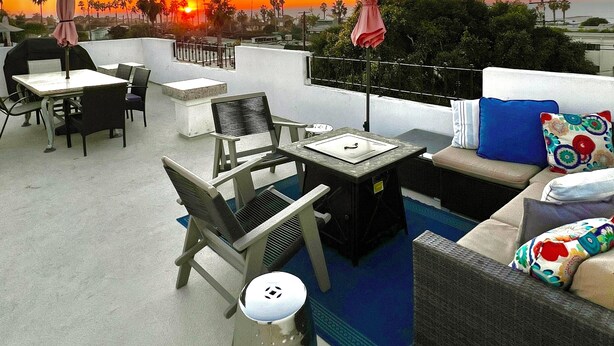 En tagterrasse med udendørs siddepladser, et lille bord og en skraldespand.