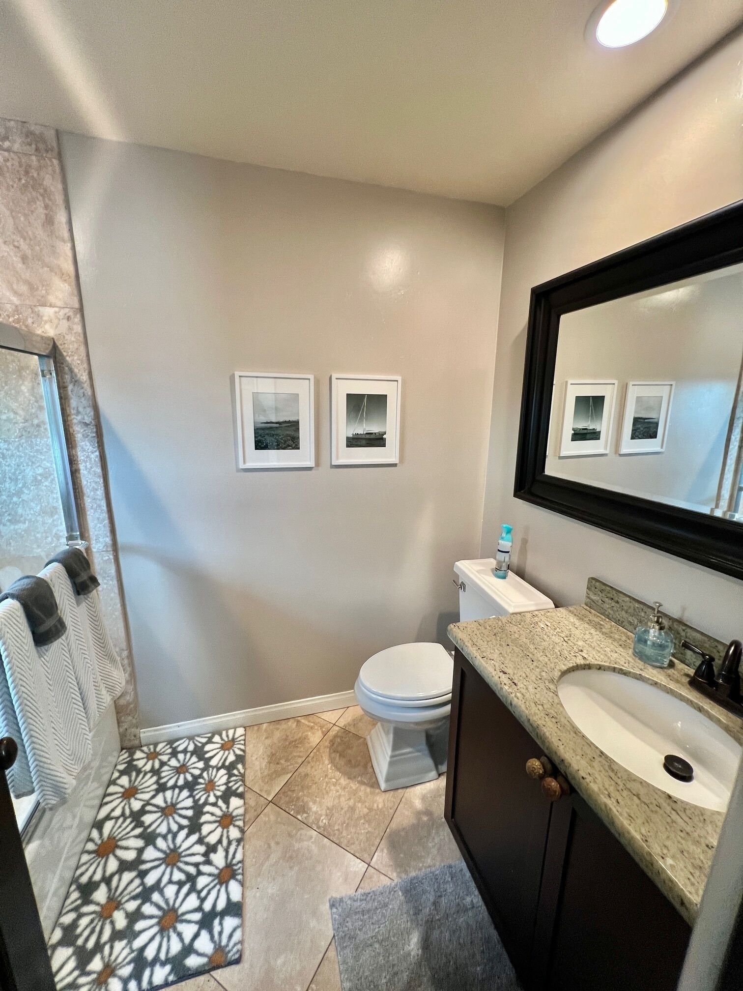 A bathroom with a toilet, sink, and framed pictures on the wall.