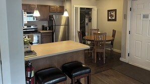 A kitchen with a central island, wooden cabinets, stainless steel appliances, and pendant lighting.