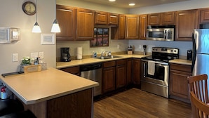 A modern kitchen with wooden cabinets, stainless steel appliances, and a central island.