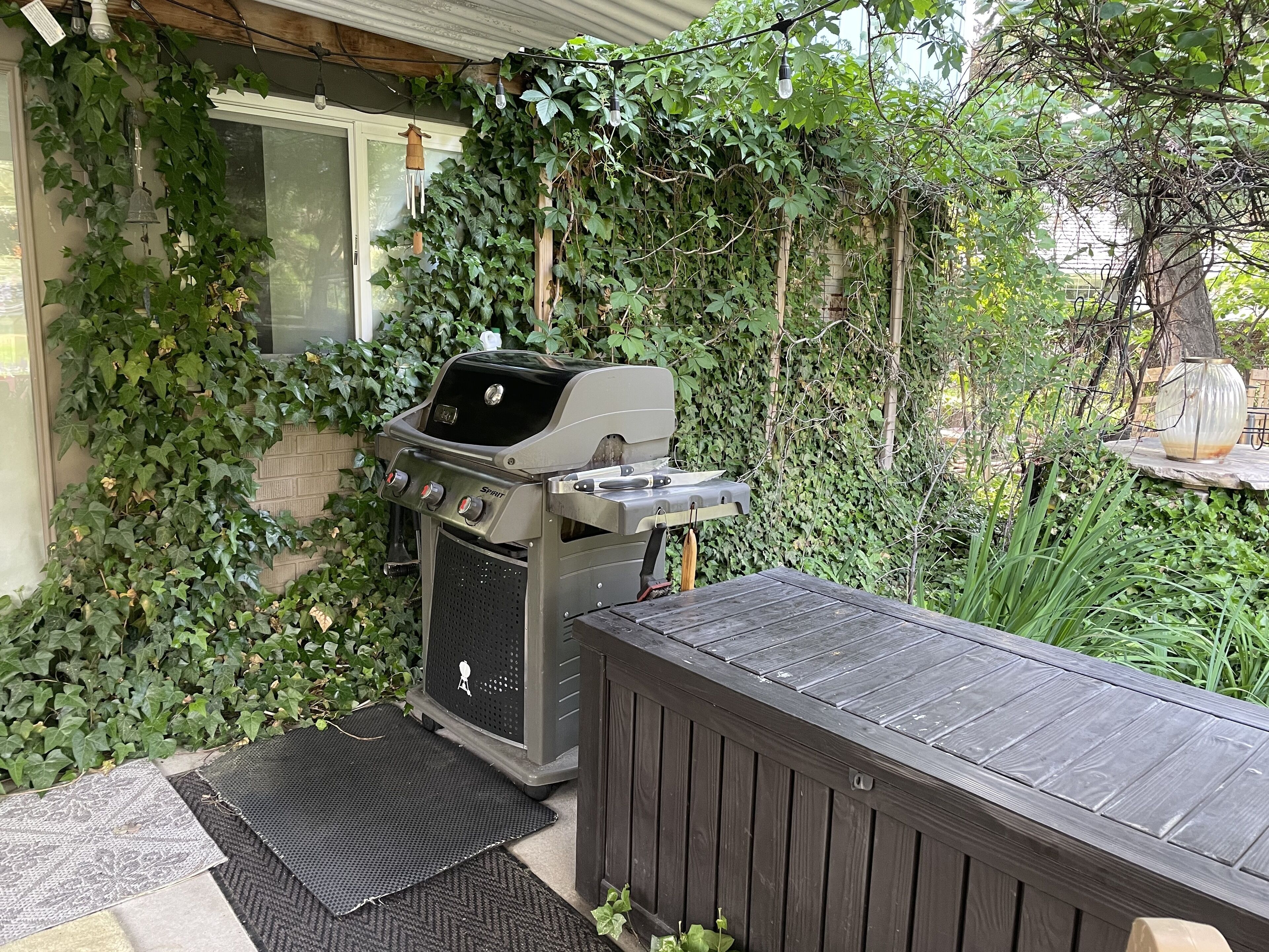 Un barbecue doté d’un ventilateur intégré, une terrasse en bois et un jardinière en pierre.