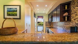 A kitchen with granite countertops, dark wooden cabinets, and a mosaic backsplash. - Condo in Kapalua!! (Maui)