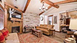 Una sala de estar acogedora con chimenea, un tapete grande y techo de madera.