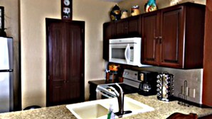 A kitchen with dark wooden cabinets, a white microwave, a toaster, and a sink.