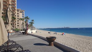 A beachside promenade with a view of the ocean, palm trees, and a distant island.