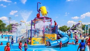 Ein Wasserpark mit verschiedenen Wasserspielgeräten, darunter eine große Wasserrutsche und mehrere Spritzzonen.