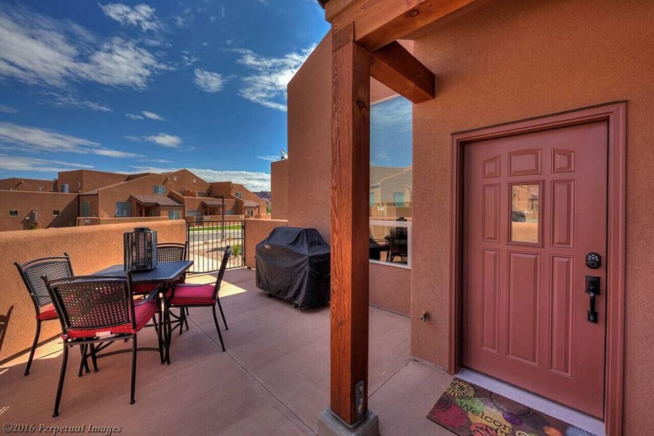 Een terras met tuinmeubilair, een barbecue en een rode deur.