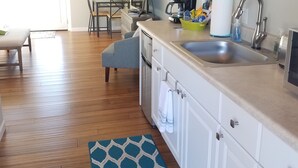A modern kitchen with white cabinets, a stainless steel sink, and a coffee maker. There is a dining area with a table and chairs, and a blue patterned rug on the floor. - PRIVATE HEATED SWIMMING POOL & HOT TUB Amazing Views, Privacy & Close to SEDONA! (Cottonwood)