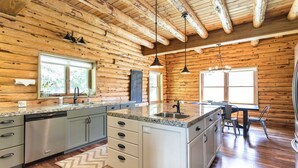 Une cuisine de style rustique, avec des comptoirs en granit, des appareils en acier inoxydable et un îlot central.